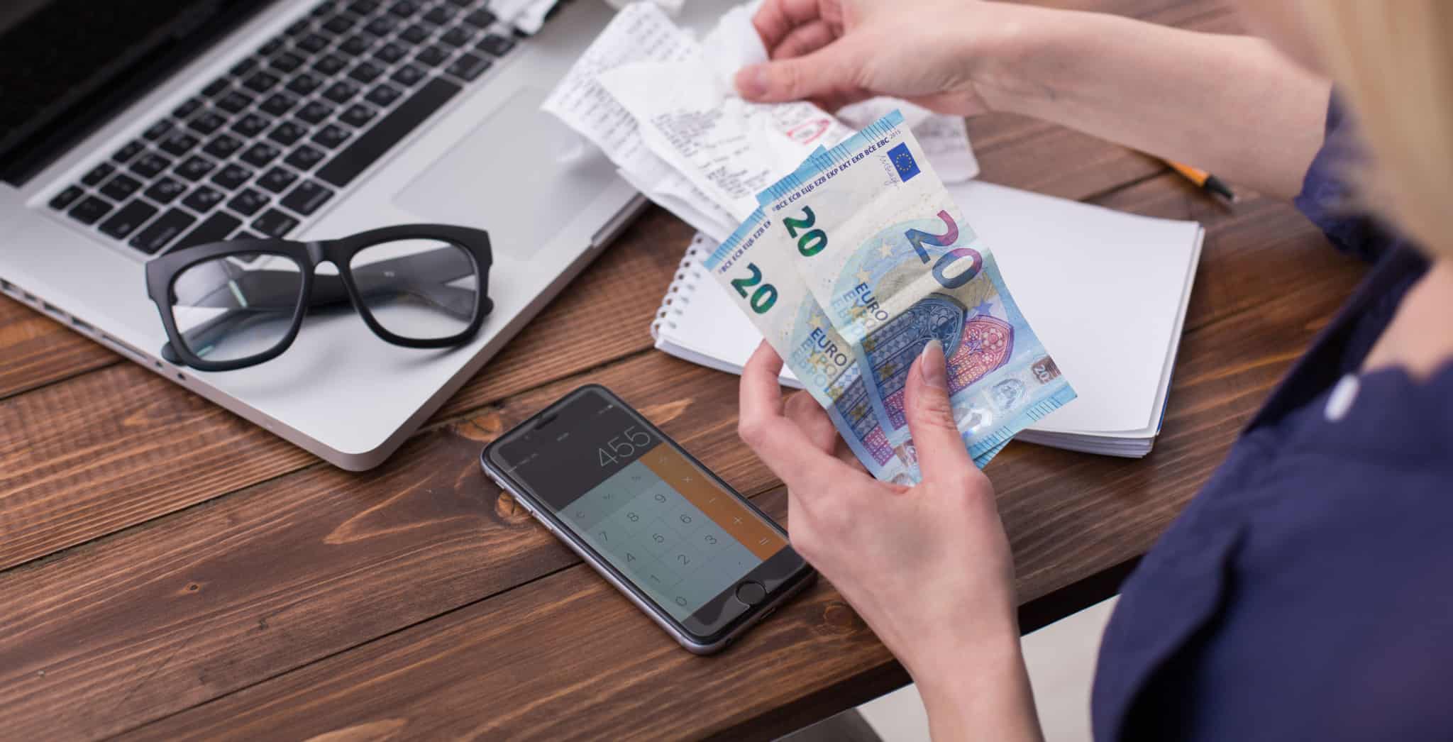 Uma pessoa a fazer contas e com notas na mão