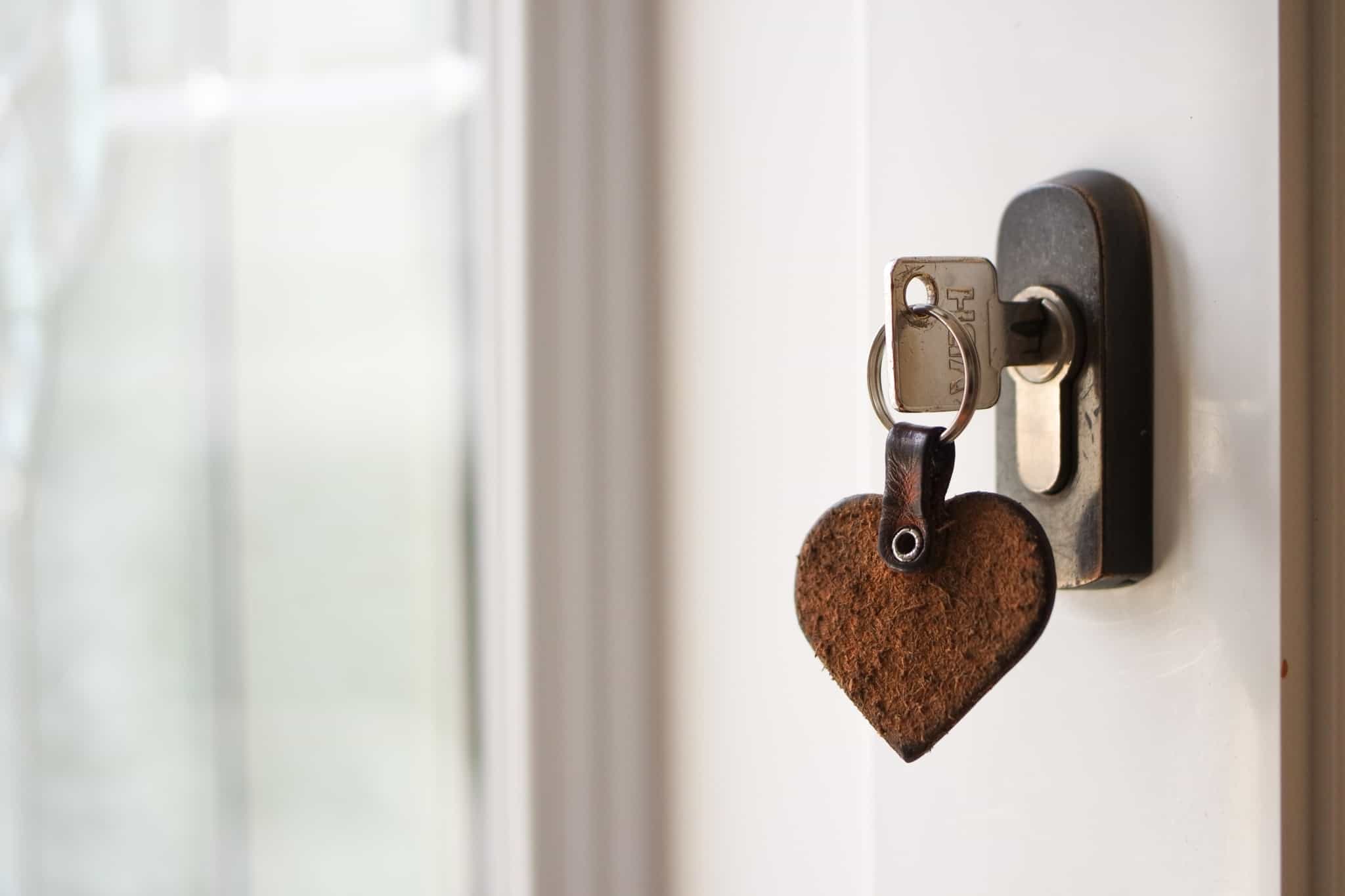 chave de casa colocada na fechadura com um porta chaves de um coraçao