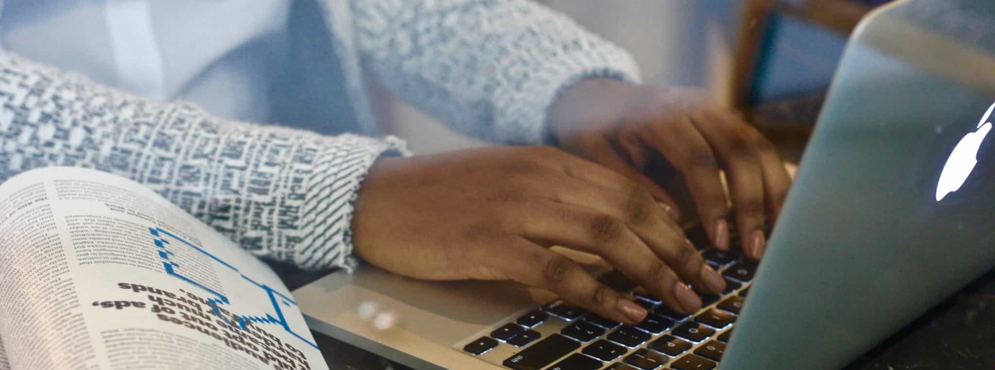 escrever no computador com uma revista aberta ao lado