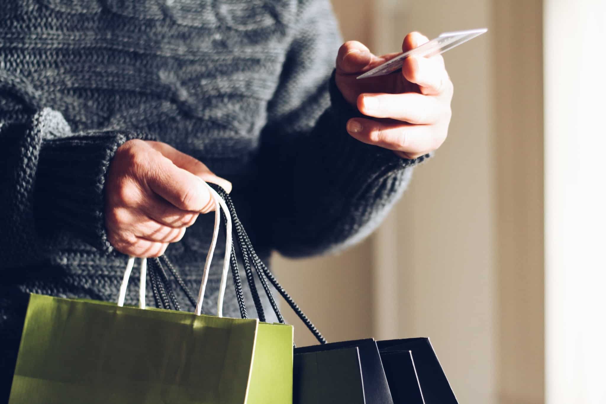 pessoa com sacos de compras e a mostrar cartao de credito