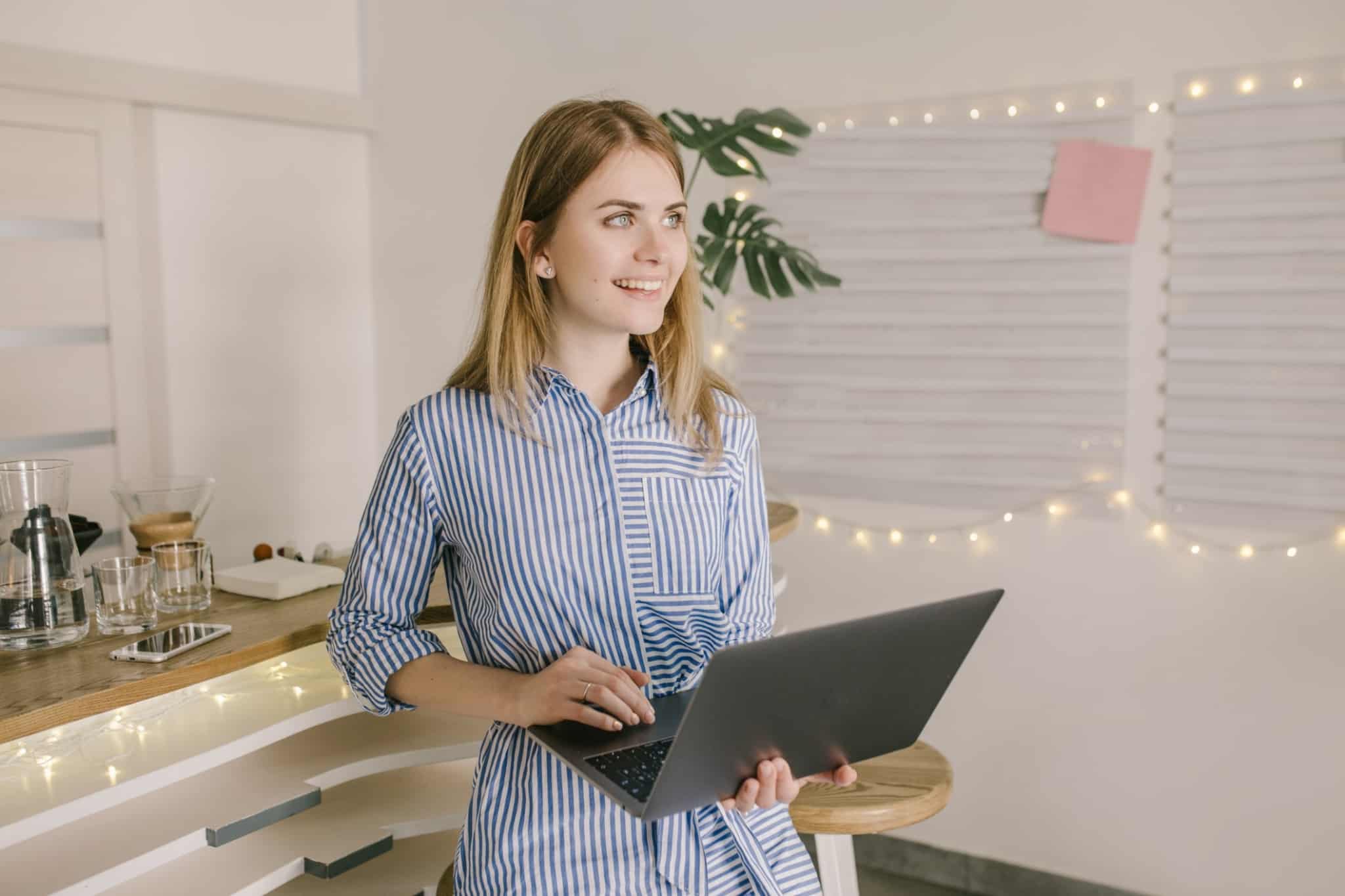 mulher loira sorridente a segurar o computador portatil na mao