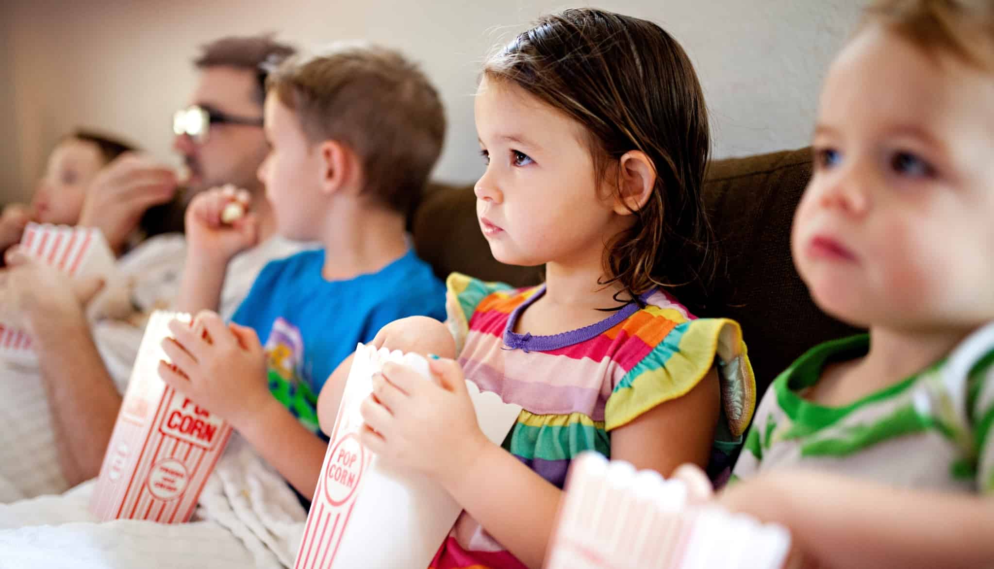 Crianças a verem um filme e a comerem pipocas