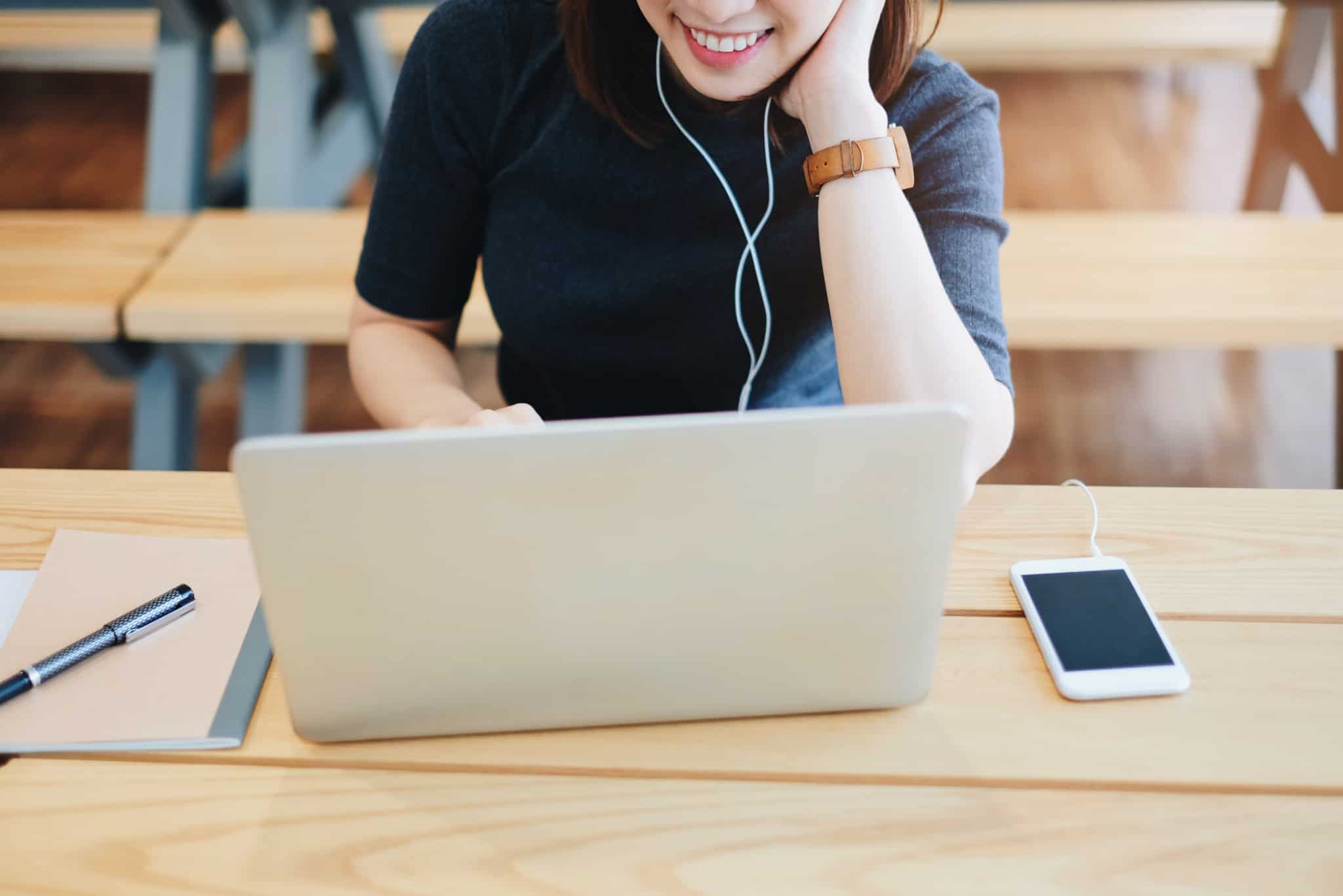 rapariga sorridente a trabalhar ao computador com os fones