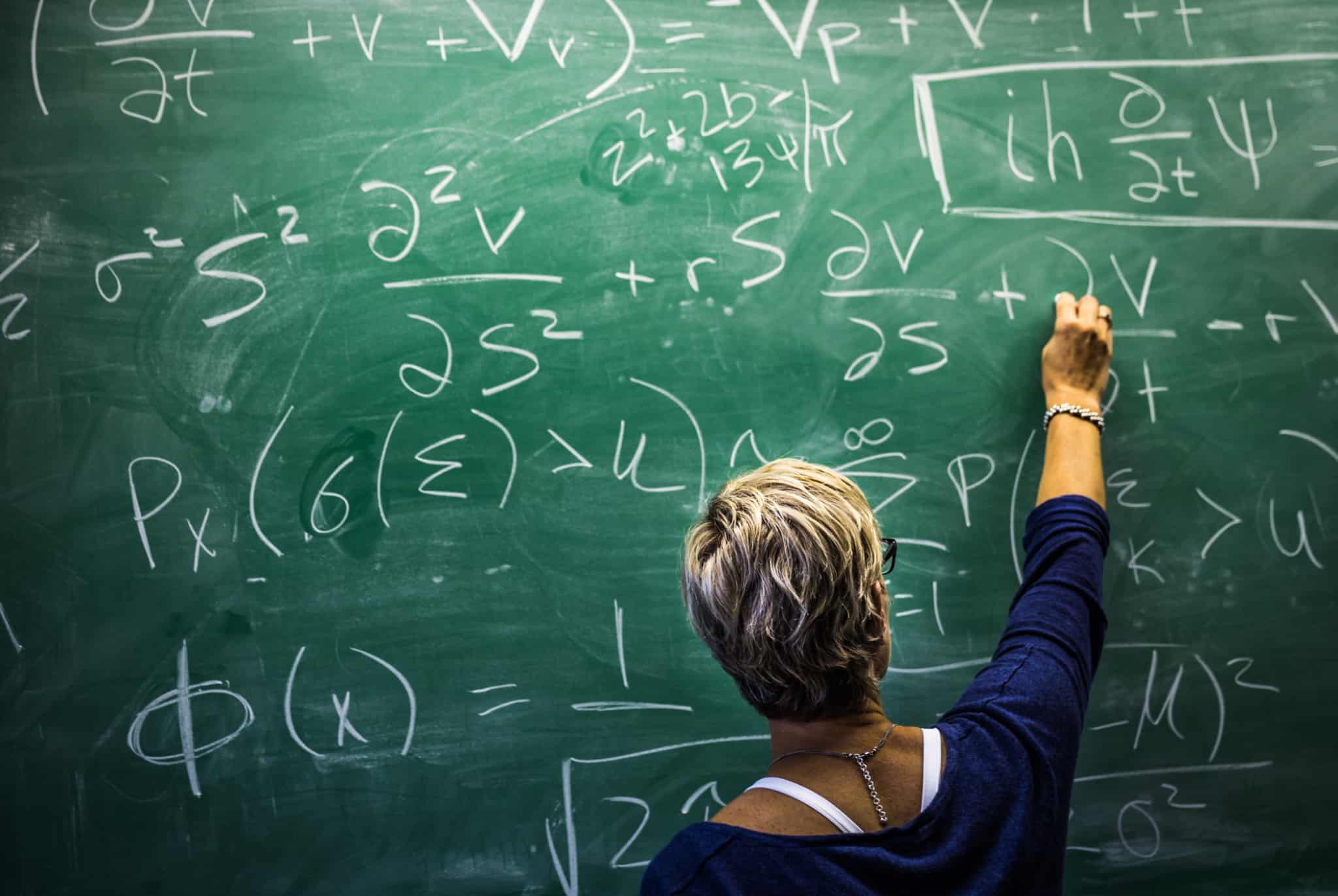 professora a escrever com um giz no quadro