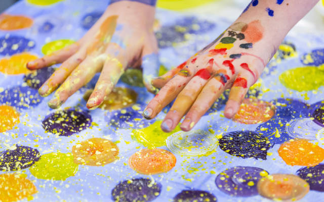 Student's hands covered in colourful paint