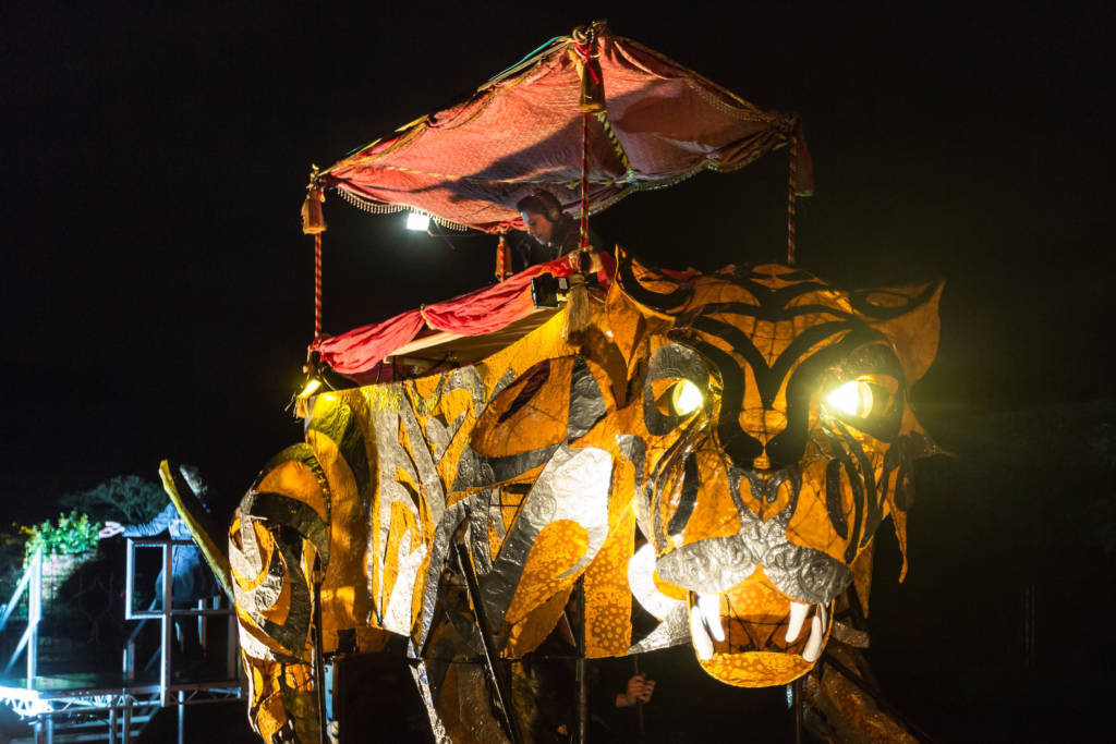 DJ performing on stage set atop a glowing lantern in the shape of a bengal tiger