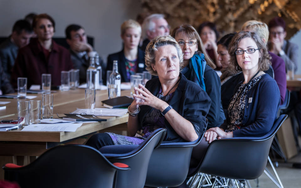 A group of Young Foundation event participants sitting around a table listening to a presentation at Windmill Hill Archive, Waddesdon with speaker off screen.