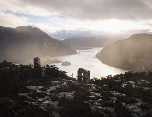 Hytter fra prosjektet "The Bolder" med utsikt over Lysefjorden og Lysefjordbroen i bakgrunnen, sett i skumringen.