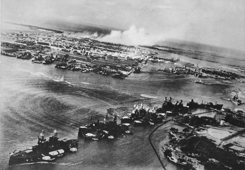 The view of battleship row from an attacking Japanese airplane, with smoke rising from Hickam Airfield in the background