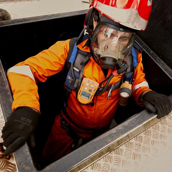 Engineer working in a confined space with a personal gas monitor clipped to his jacket