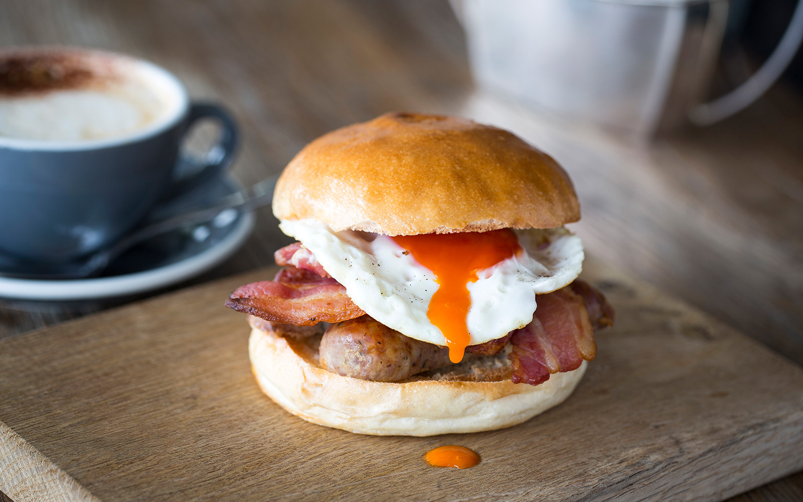 Visit Swan Bar | Breakfast brioche Photo of a breakfast brioche bun with cumberland sausage, smoked streaky bacon and a legbar fried egg.