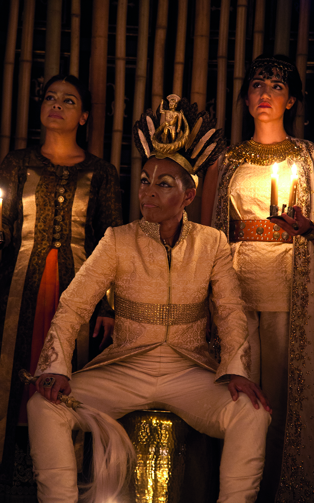 Richard II Sam Wanamaker Playhouse An actor in a white suit sits on a throne wearing a gold crown