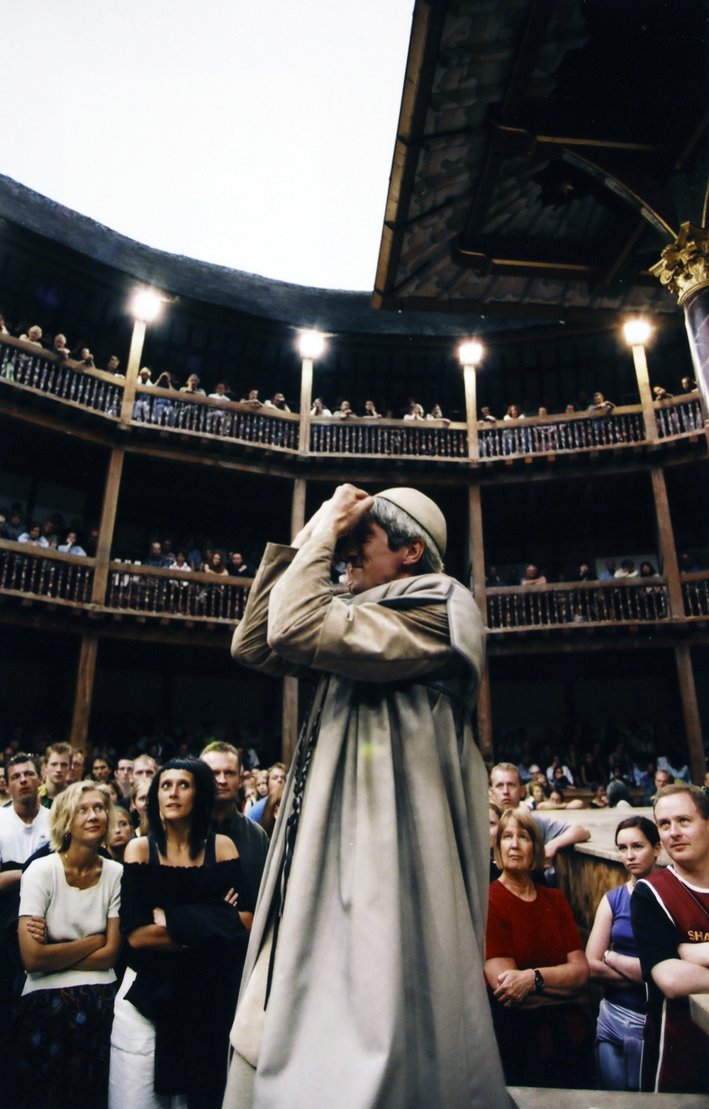 Actor Audience Antony and Cleopatra Shakespeare's Globe A man holding his hands up to his face stands in the Yard of the Globe Theatre, surrounded by audience members.