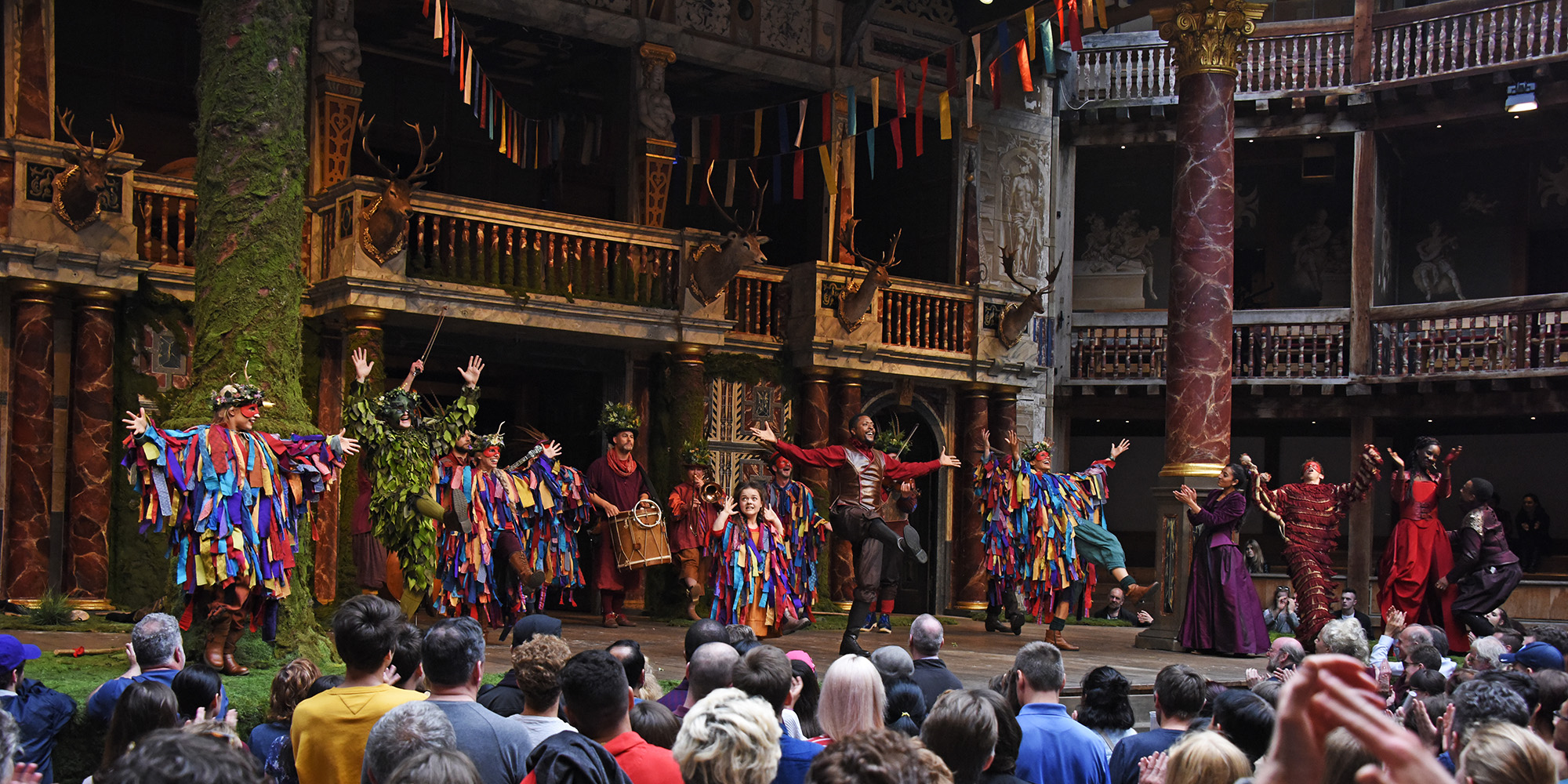 The Two Noble Kinsmen Watch A group of actors wearing brightly coloured costumes dance on the Globe Theatre stage