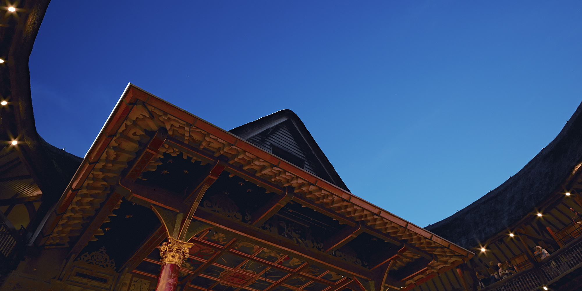 Globe Theatre blue sky Shakespeare's Globe A bright blue evening sky above a circular timber theatre, with pointed thatched roof.