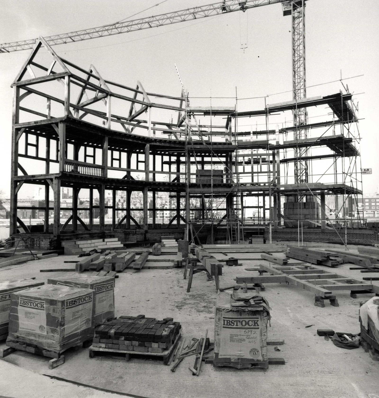 Globe Theatre construction timber with crane A timber circular structure starts to take shape on a construction site, with a crane in the background.