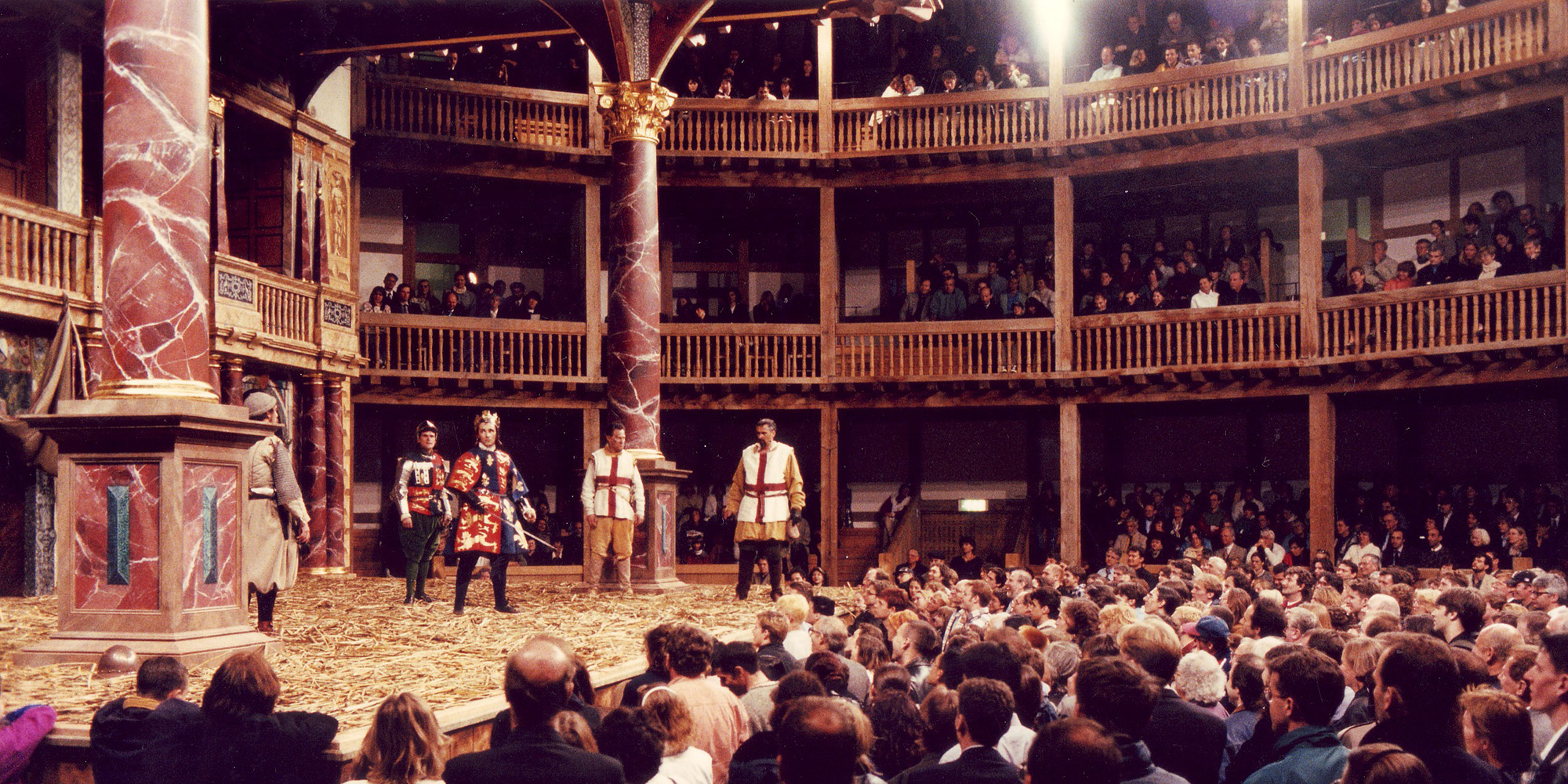 Henry V Globe Theate 1997 Company Shakespeare's Globe 2 A large crowd of audience members stand watching a play in a circular timber structure.