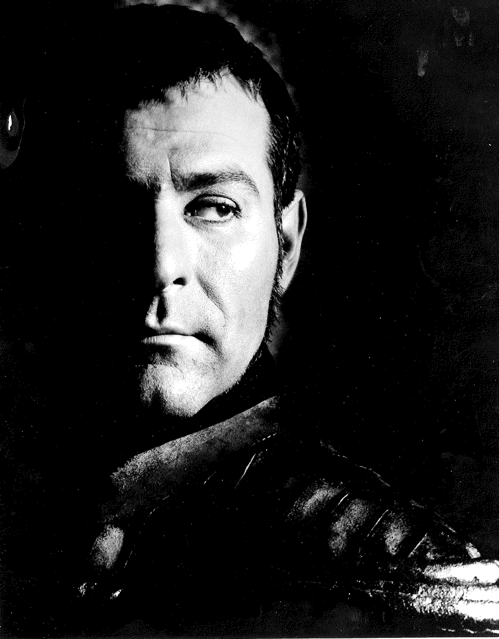Sam Wanamaker Iago Shakespeare's Globe A man stands in the shadows.