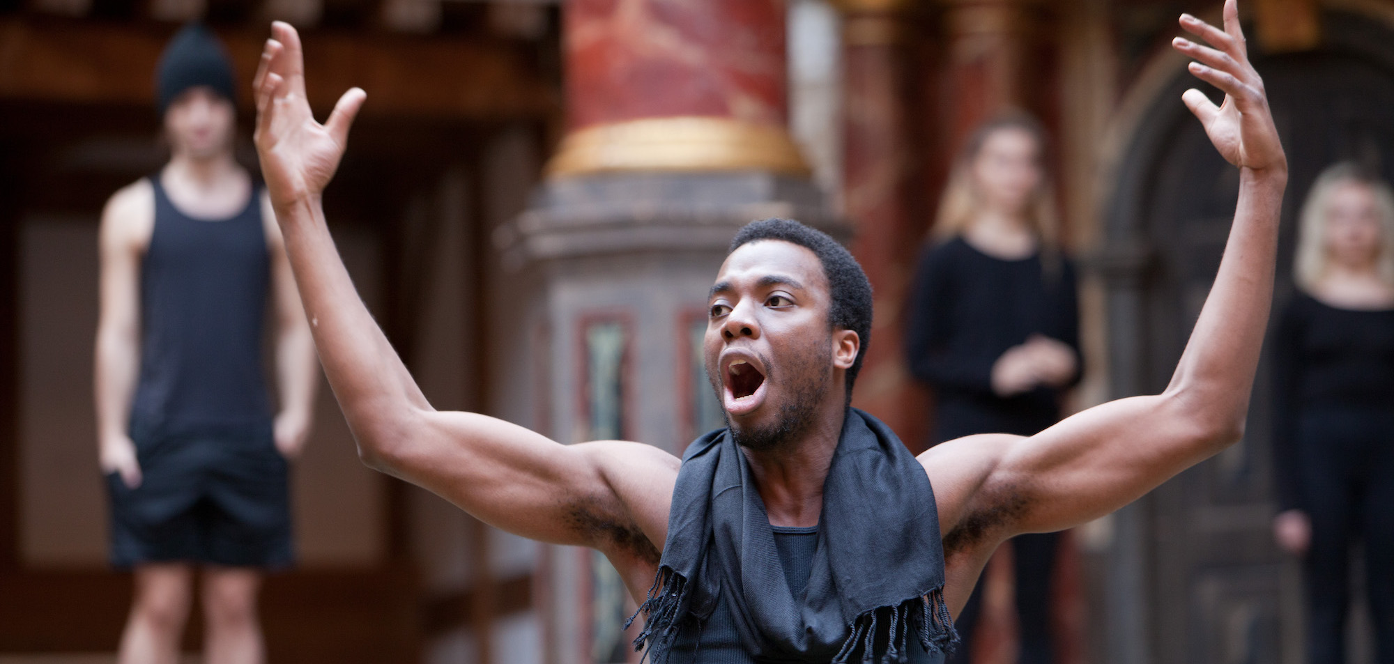 Higher Education A student raises his hands in the air acting in a performance