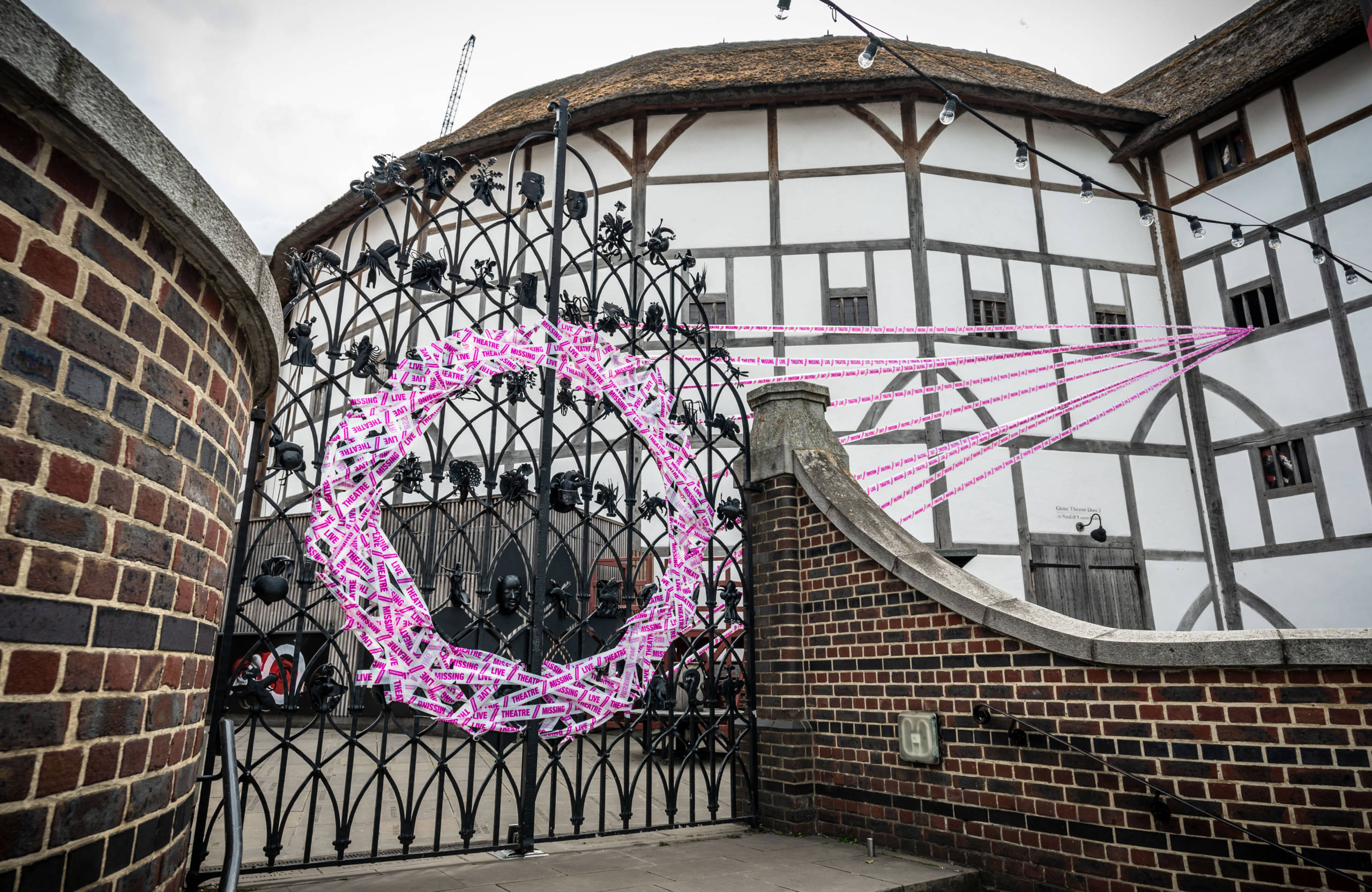 Scene Change Globe-102 Flush White and pink tape forms a circle on a set of iron gates.