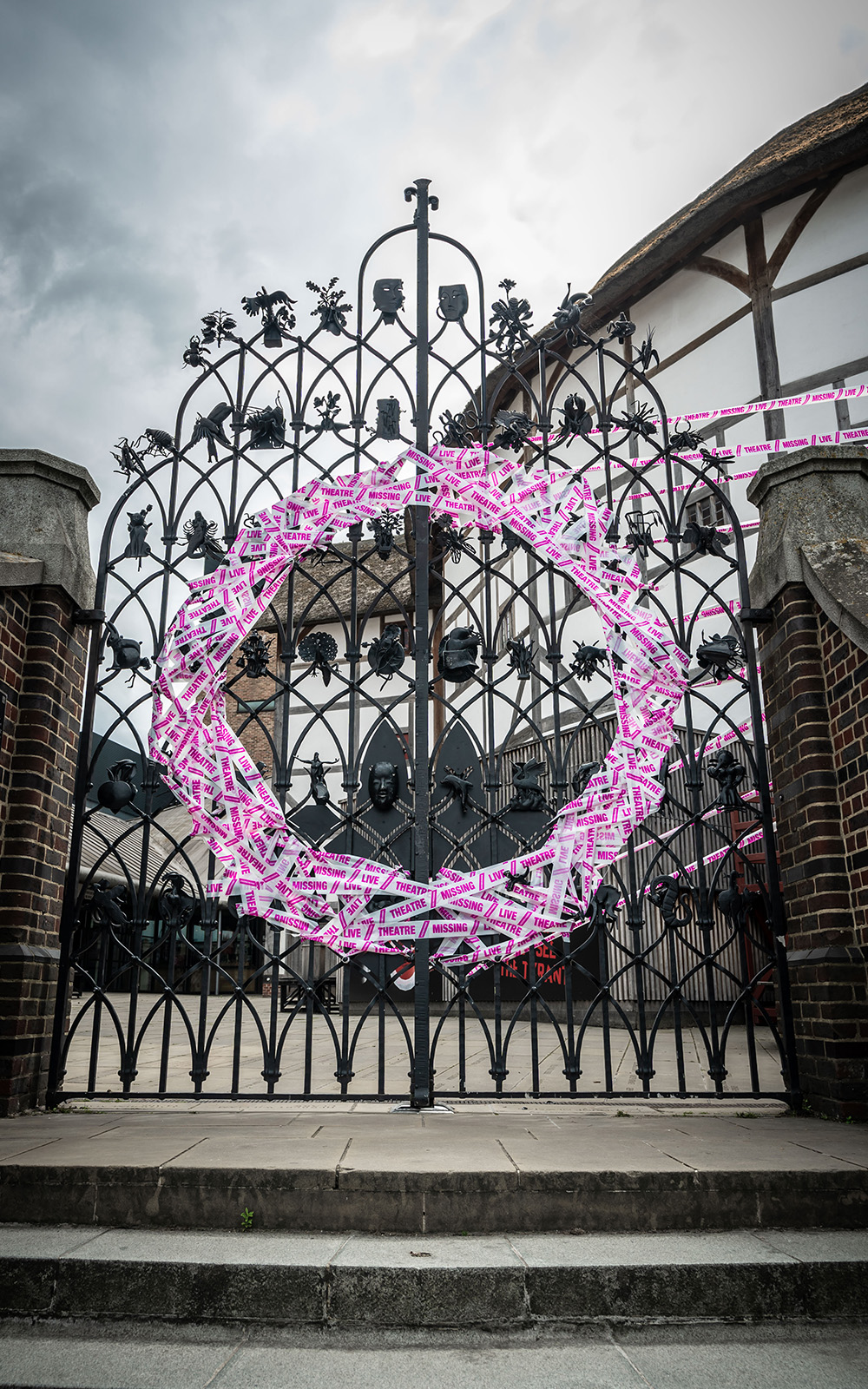 Scene Change Globe-251 White and pink tape forms a circle on a set of iron gates.