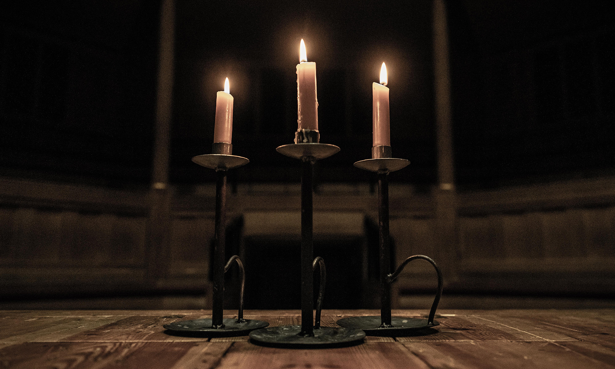 Candles flush Deep Night Dark Night Shakespeare's Globe Three lit candles in the dark shadows of an indoor wooden theatre.