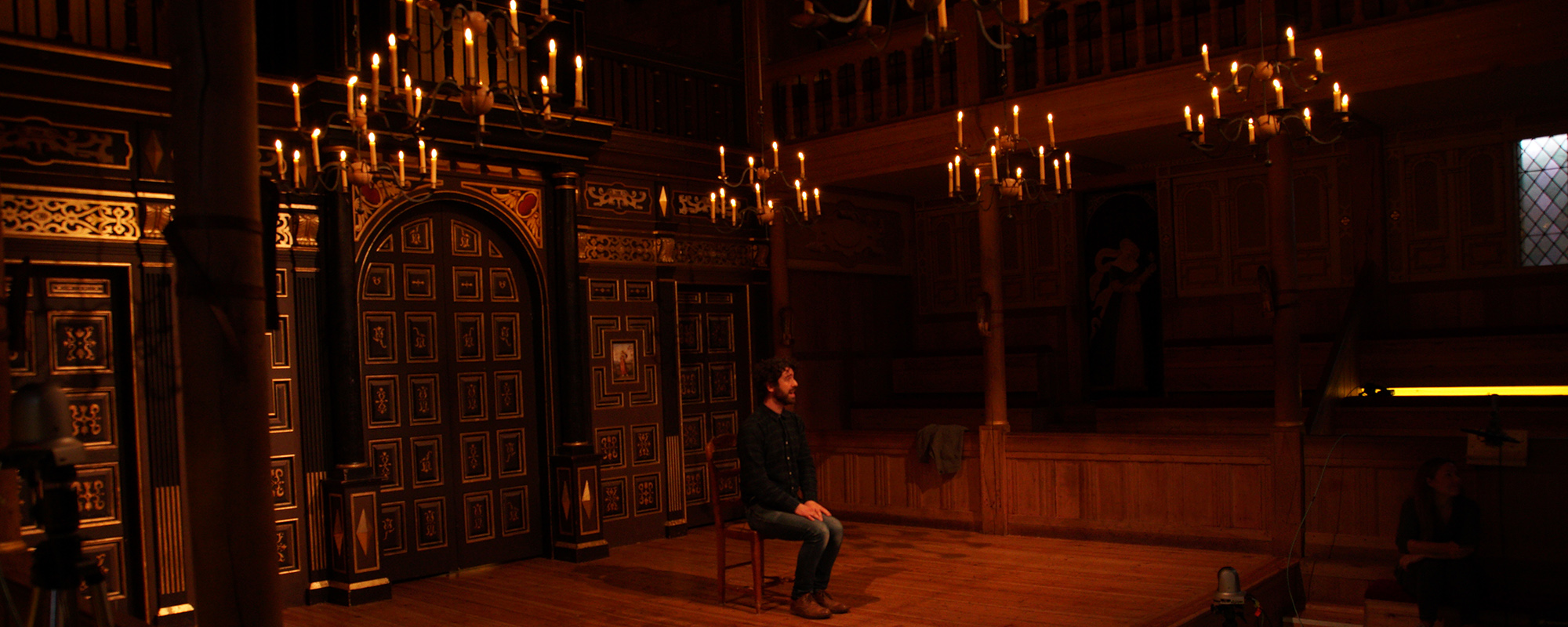 Such Stuff S7 E1 Ghost stories masthead An actor sits on the stage surrounded by the candlelight of the indoor playhouse