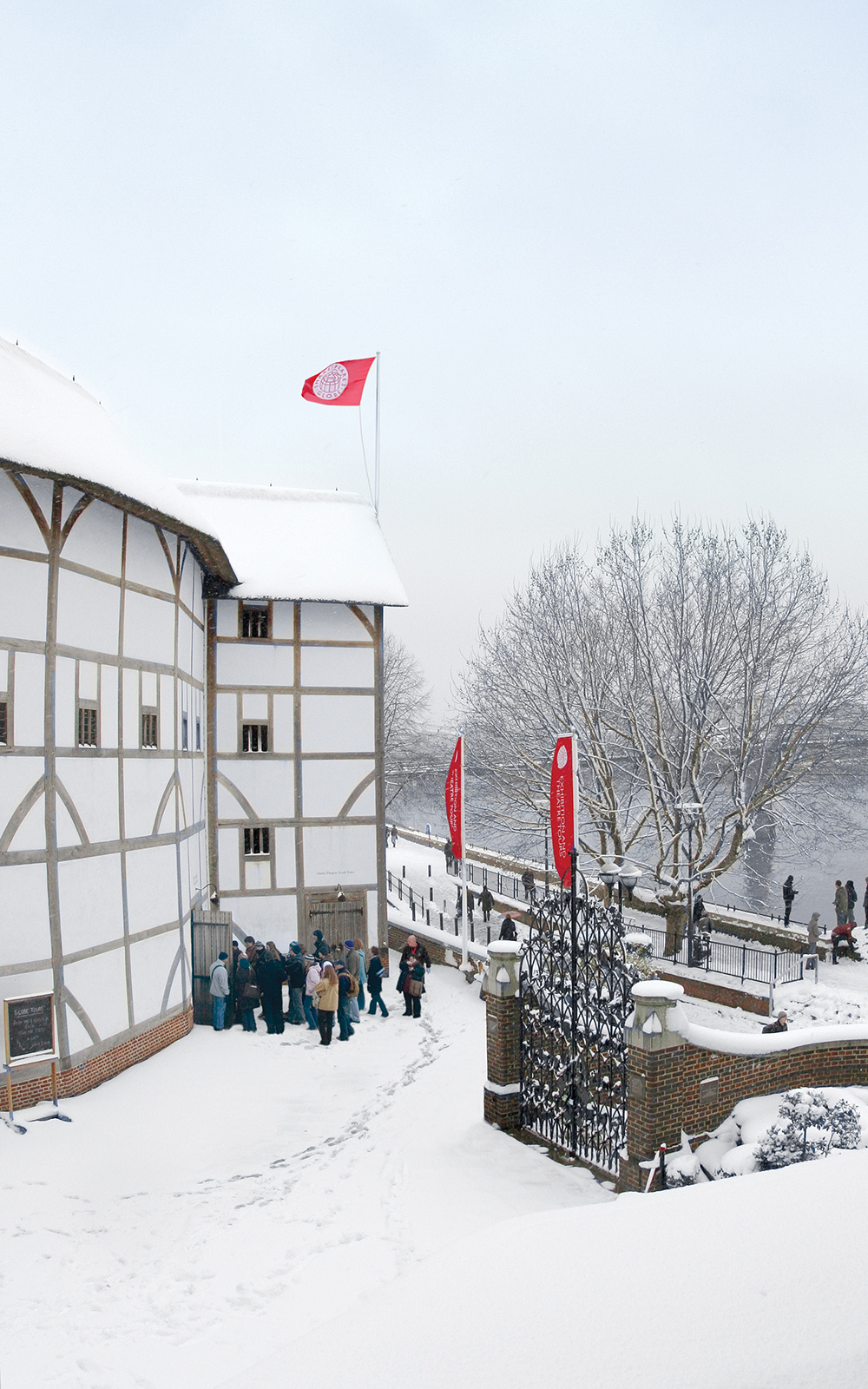 Shakespeare's Globe Snow Frost Fair Globe Advent Winter A snowy view of the white circular timber structure theatre, with the bank of the River Thames infront