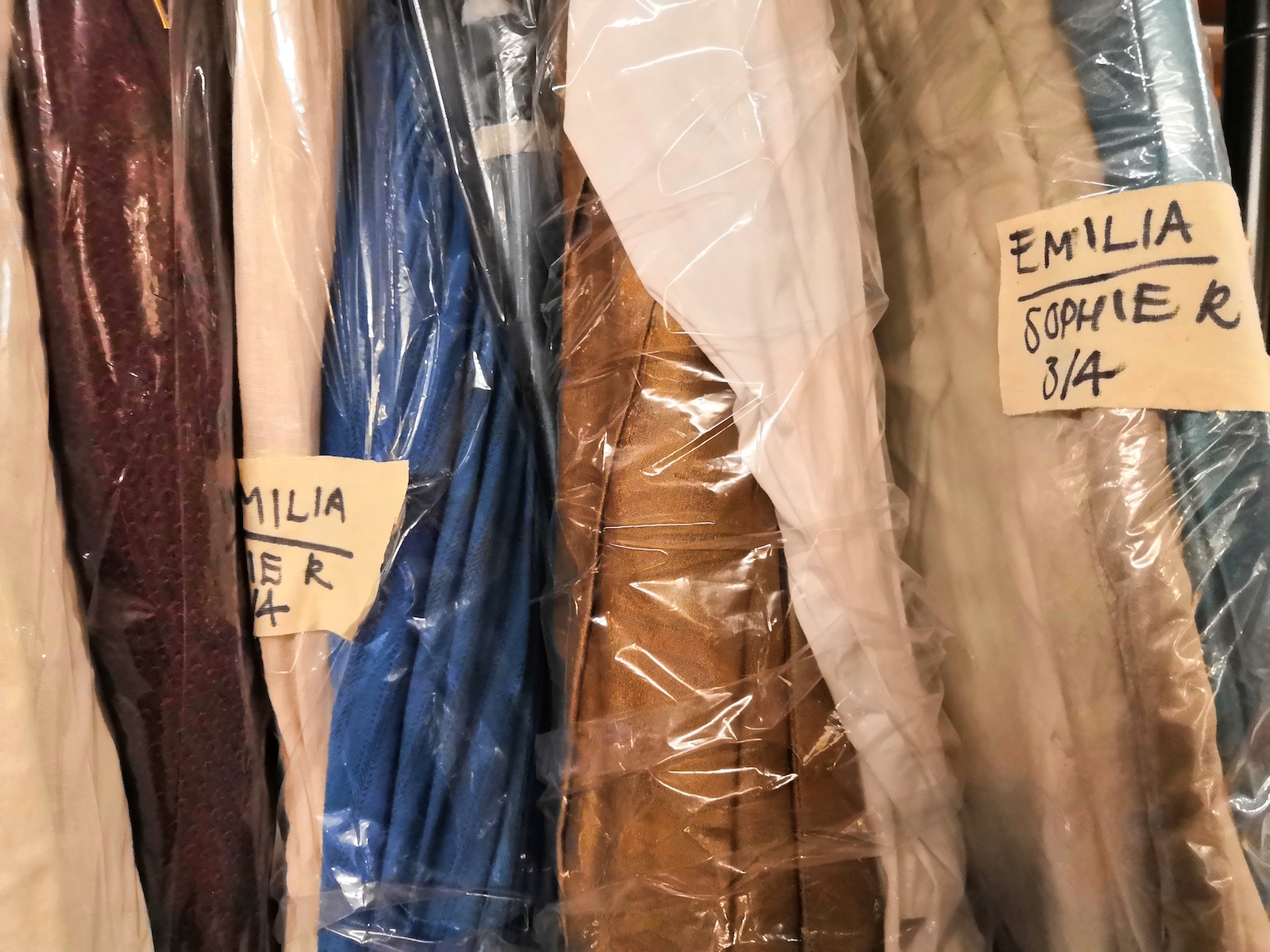 Emilia Costume Design Jo Scotcher Shakespeare’s Globe Costumes in a theatre are wrapped in film and sit next to each other on a rail