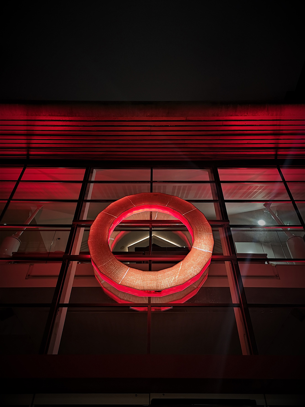 Light It In Red March 2021 Shakespeare's Globe 6 The red circular logo of Shakespeare's Globe is backlit by red light.