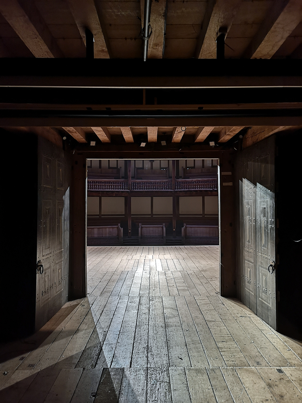 Spring Globe Theatre Tiring House Reopening 2021 A view from backstage of the Globe Theatre, looking out through the open double oak doors on to the stage and the galleries beyond.