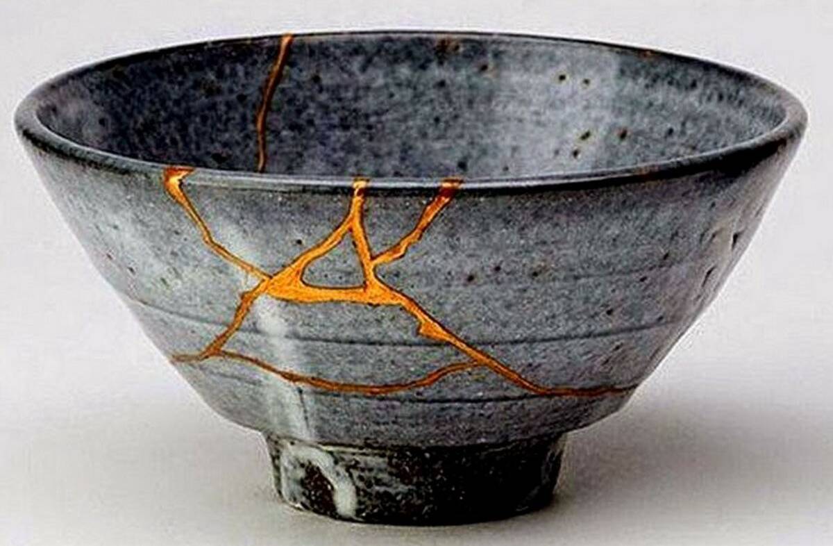kintsugi A grey speckled bowl that has been cracked and repaired with golden lacquer.