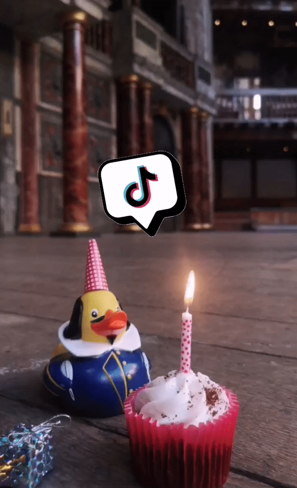 Quackspeare TikTok Shakespeare's Globe A rubber duck dressed as Shakespeare wears a red party hat and blows out a lit candle on a cupcake, with a TikTok speech bubble above his head.