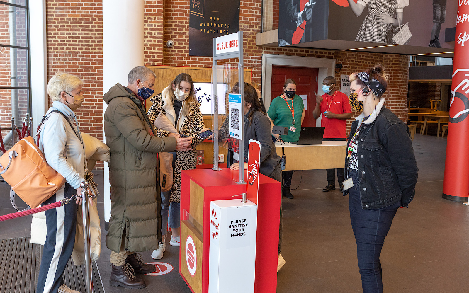 Covid Coronavirus Shakespeare’s Globe Pete Le May 2021 An audience member shows a ticket on their phone to a member of staff who stands behind a perspex stand