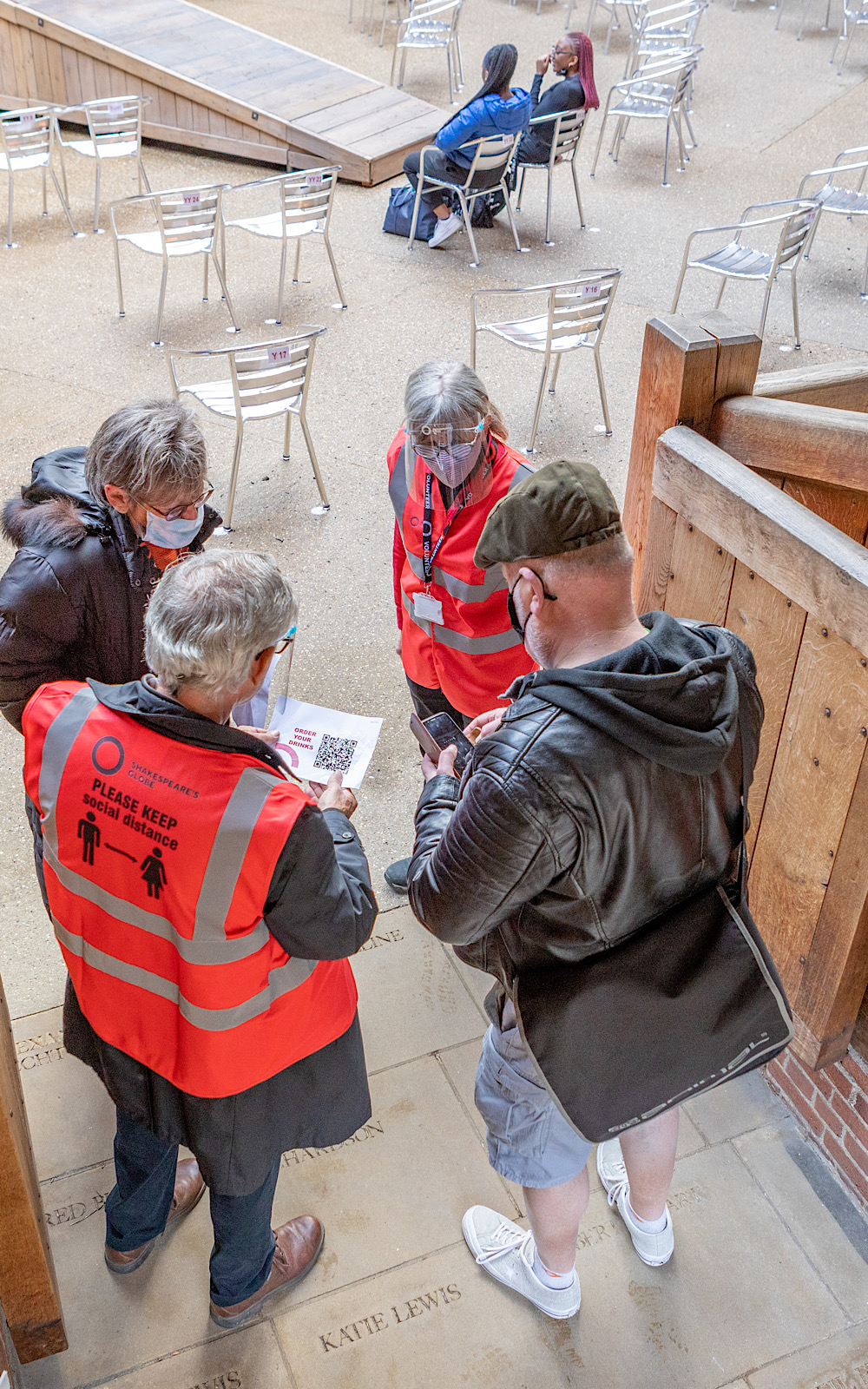 Covid Coronavirus Shakespeare’s Globe Pete Le May 2021 Members of staff in high-vis jackets talk to audience members as they enter an outdoor theatre