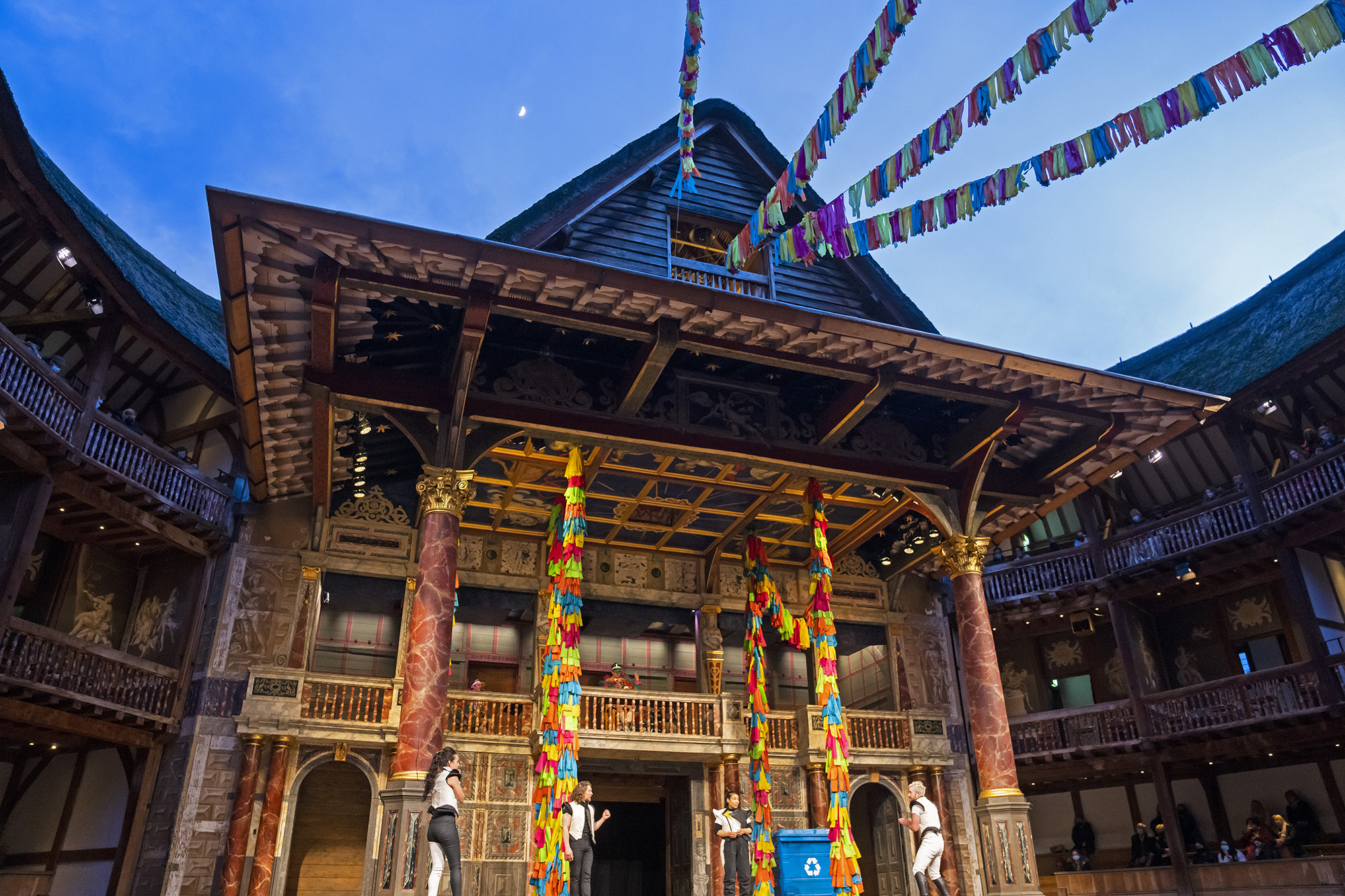 Reopening Blog A Midsummer Night's Dream 2021 Shakespeare's Globe A twilight night sky, with a glimpse of the moon, shines above the Globe Theatre stage: with colourful streamings hanging across the open-air roof.