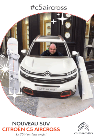 Un GIF animé pris avec le photobooth de Josepho montre un homme derrière une pancarte en forme de voiture et des flocons qui scintillent. Le GIF est personnalisé avec le logo Citroën et le nom du modèle de voiture le nouveau SUV Citroën C5 Aircross. Le GIF est pris devant un magasin..