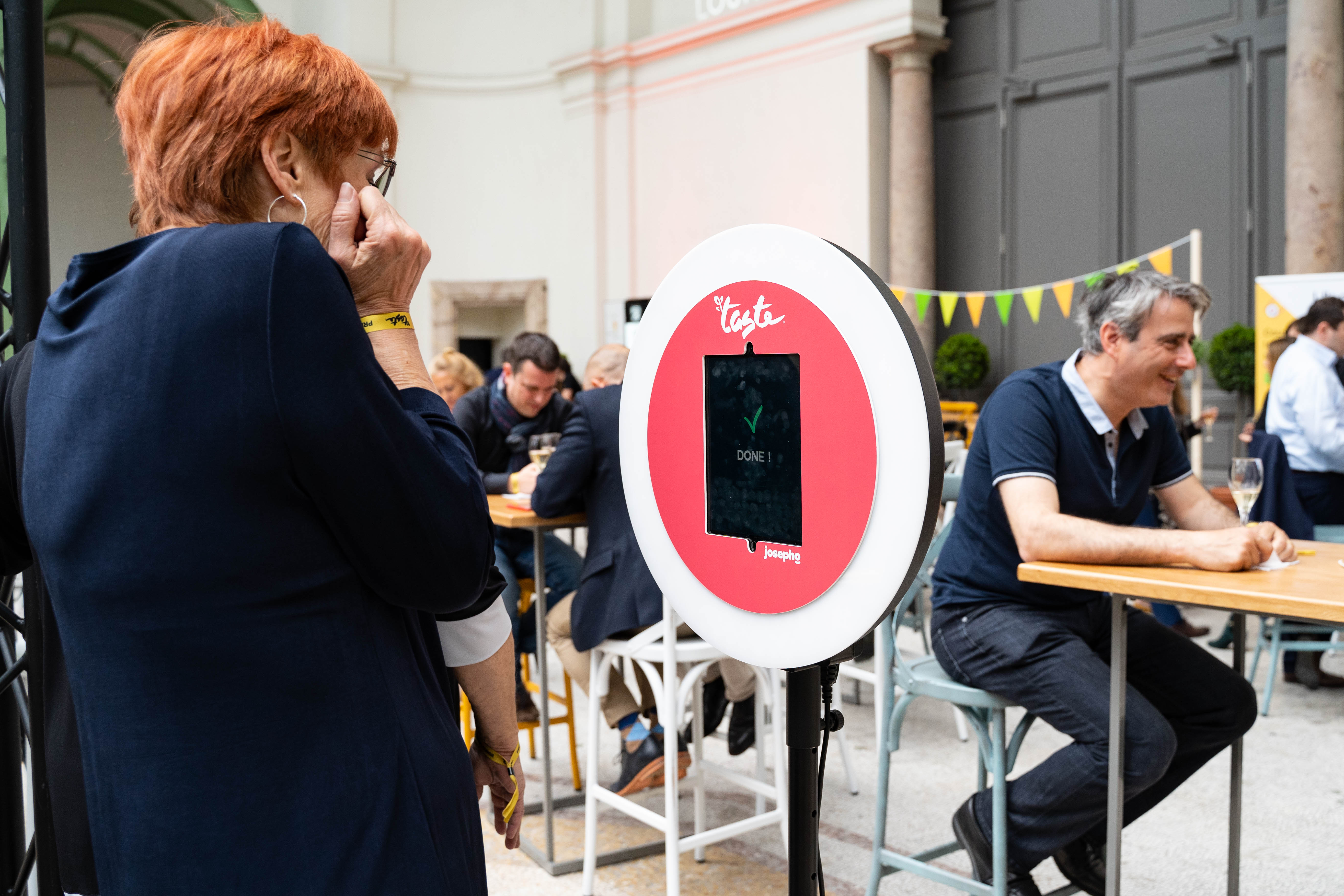 Sur le salon Taste of Paris, une femme se prend en photo avec le photobooth de Josepho personnalisé avec les couleurs et le logo Taste of Paris.