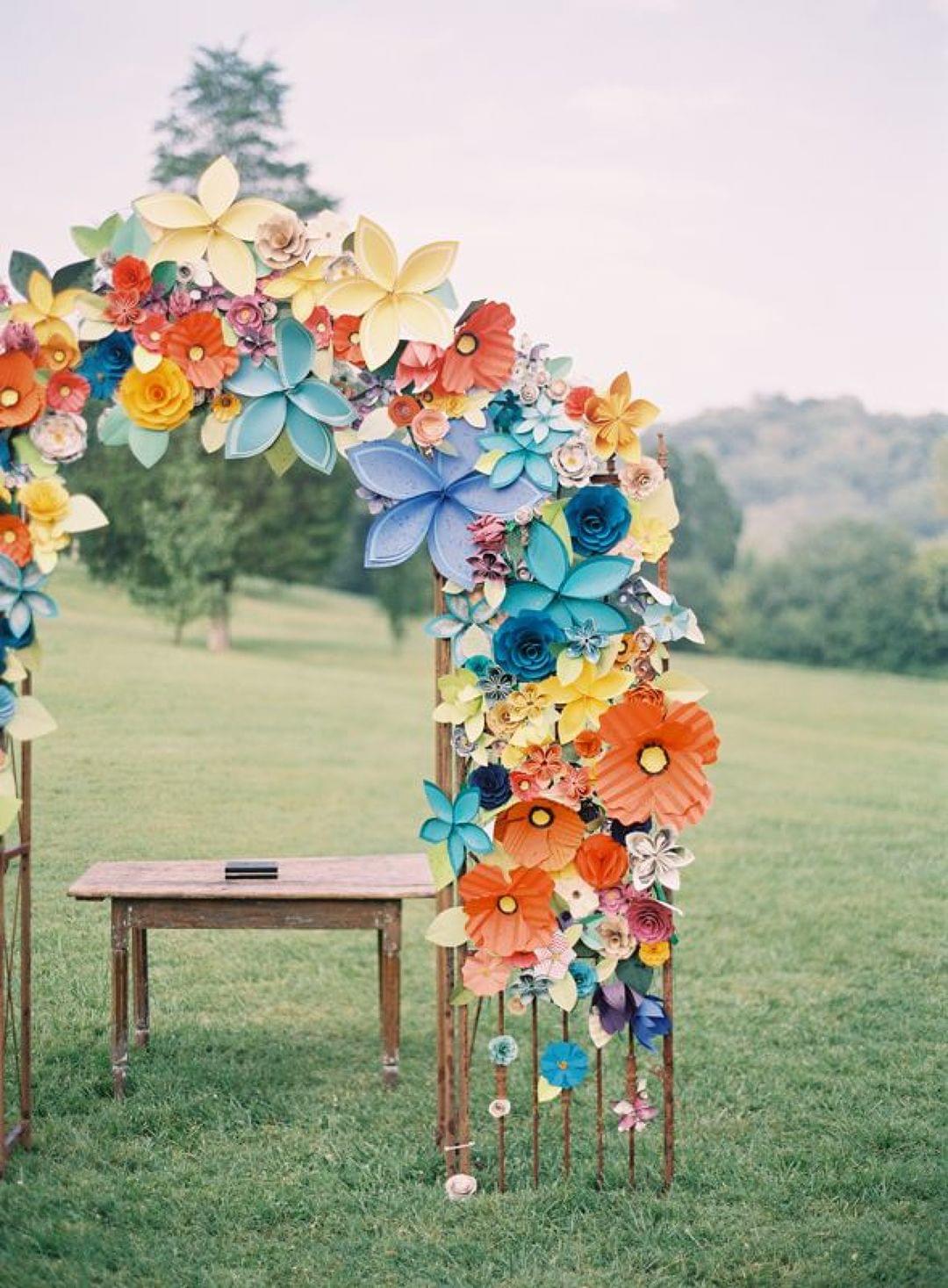 Un photocall, réalisé avec des fleurs en papier, est positionné dans un champ.