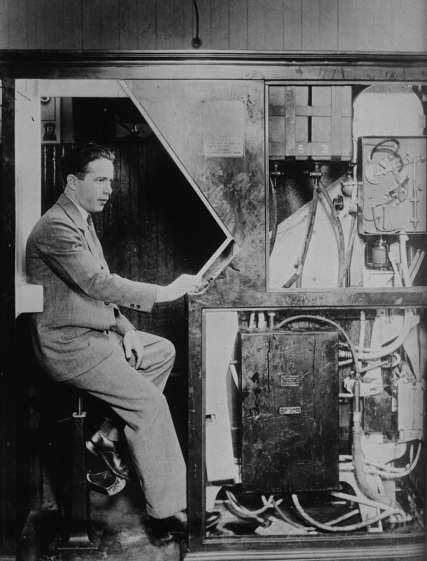 Anatol Josepho qui présente sa cabine photographique, l'ancêtre du photomaton.