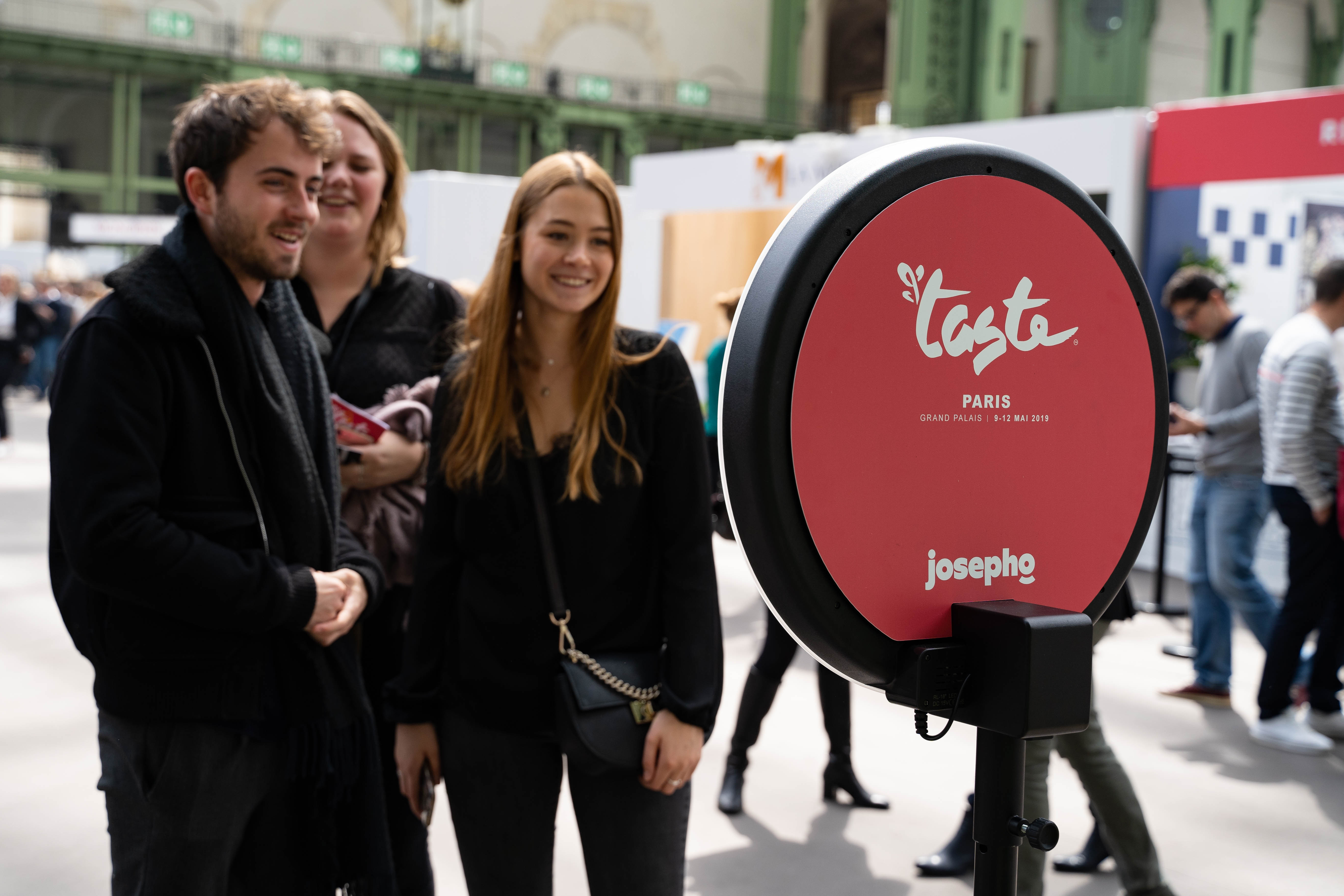 Sur le salon Taste of Paris, trois personnes se prennent en photo avec le photobooth de Josepho personnalisé avec les couleurs et le logo Taste of Paris.