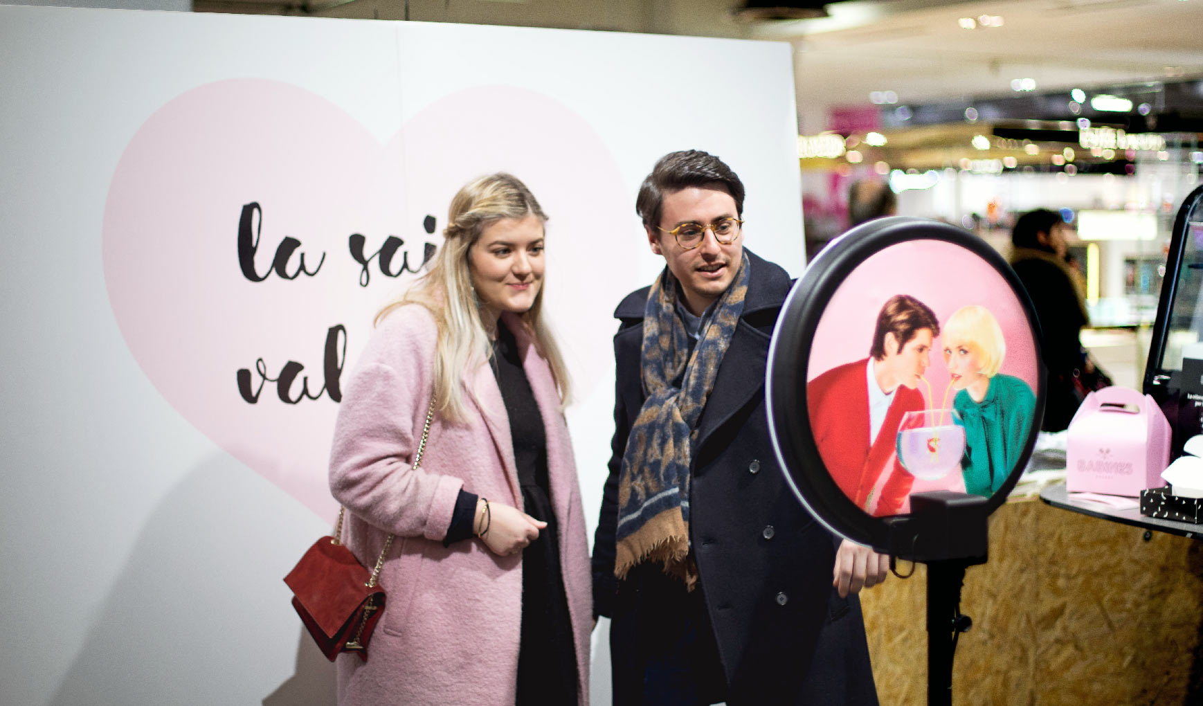 Un couple se prend en photo avec la borne photo photobooth Josepho dans le magasin Galeries Lafayette de Paris.