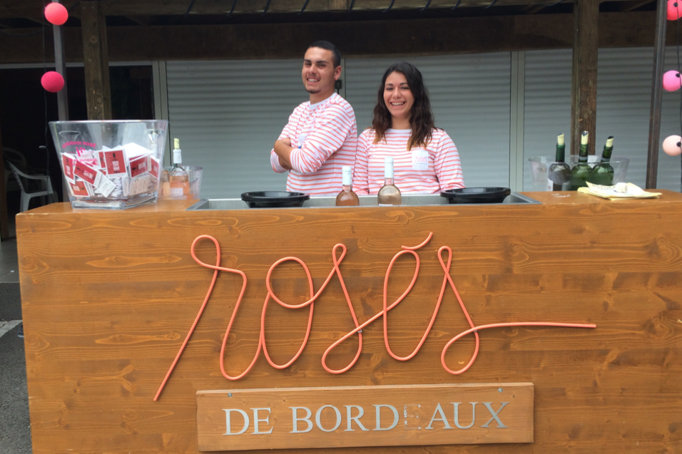 Les serveurs derrière le stand Rosés de Bordeaux prennent la pose et sourient.