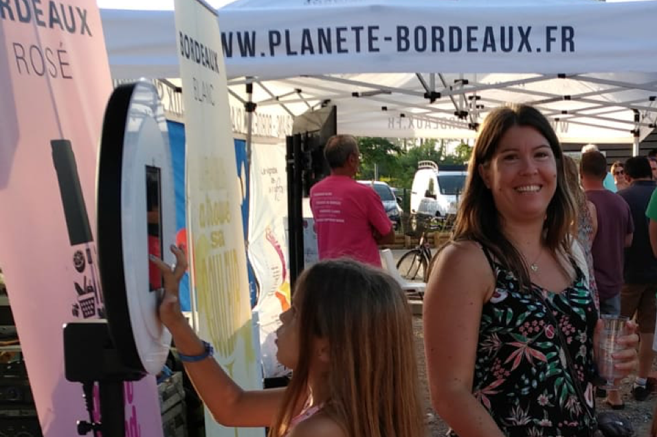 Une fille se prend en photo avec le photobooth de Josepho et sa mère sourit.