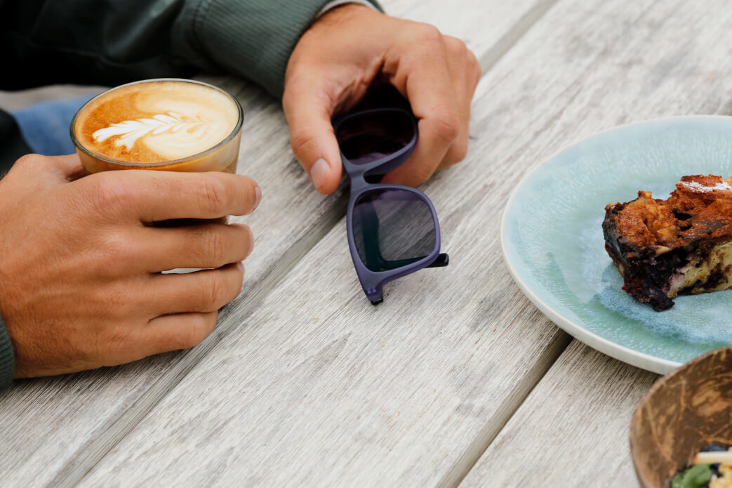 Marcello holding DUNBAR SUN RX on table drinking coffee