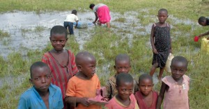 Burundian children are fetching water from a pond formed by the leakage of a pipeline in a settlement area in Uganda.