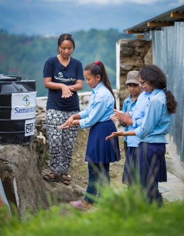 Staff member Sujana Lama teaches hand-washing techniques to schoolchildren.