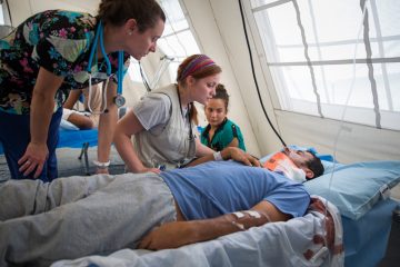 Lider receives an examination with his niece, Maria, by his bedside.