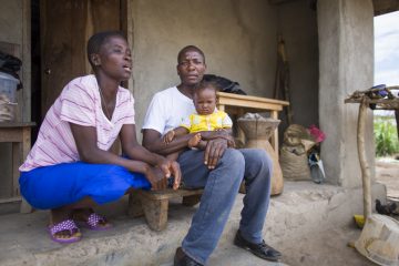 Harrison Sakela, the first Ebola survivor in Liberia, sits outside his home with his wife and young daughter.