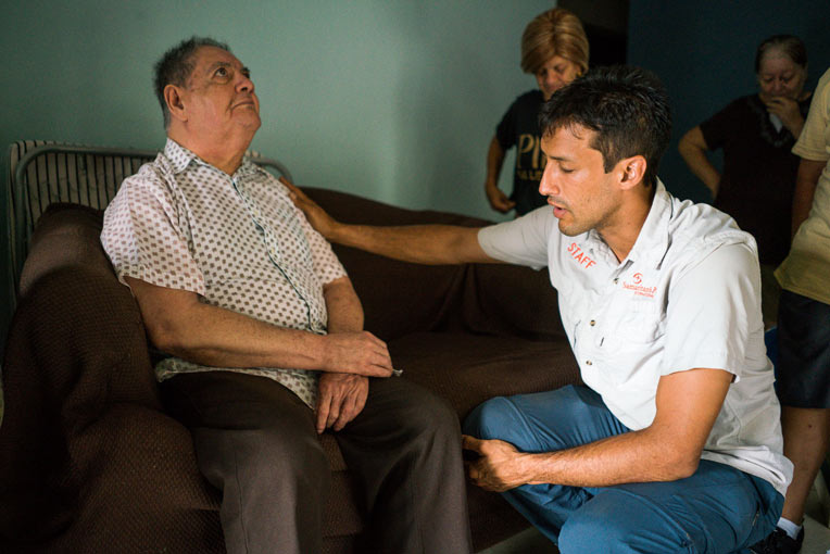 Andres Morales prays with Eugenio Rodriguez who received a generator from Samaritan's Purse.